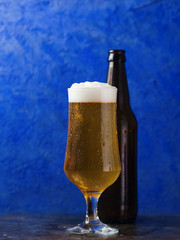 Cold Beer lager glass and beer bottle on a dark background close up with water drops