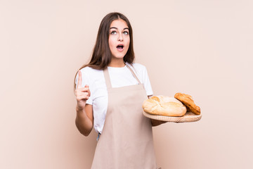 Young caucasian baker woman isolated pointing upside with opened mouth.
