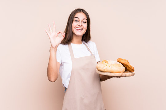 Young caucasian baker woman isolated cheerful and confident showing ok gesture.