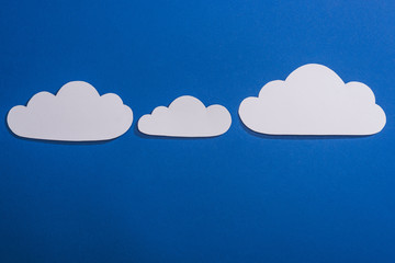 top view of white paper cut clouds on blue background