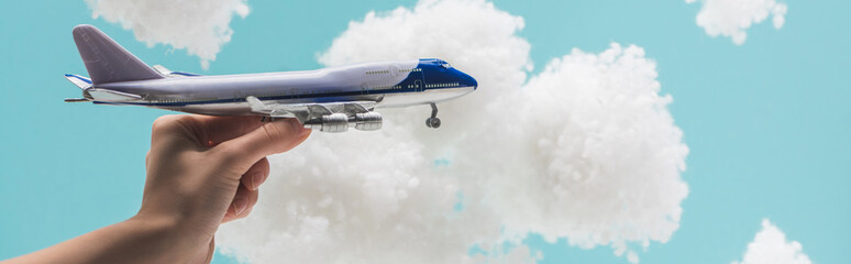 cropped view of woman playing with toy plane among white fluffy clouds made of cotton wool isolated...
