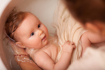 cute newborn baby bathes in the bathroom. The concept of a toddlers ' swimming