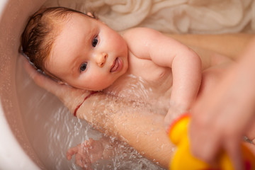 cute newborn baby bathes in the bathroom. The concept of a toddlers ' swimming