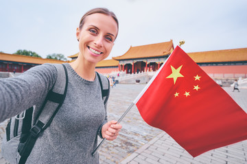 Enjoying vacation in China. Travel and technology. Young woman with national chinese flag taking...