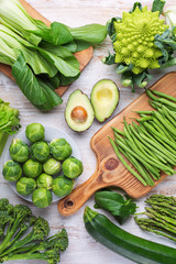 Clean eating concept. Green vegetables on white table broccoli sprouts peas avocado courgette beans bok choy celery, top view, selective focus