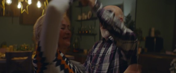 Senior couple dancing in the kitchen at home on a Christmas Eve. Decorated interior in the background. Shot on ARRI Alexa Mini with Cooke 2x Anamorphic lenses. 4K UHD RAW Graded footage
