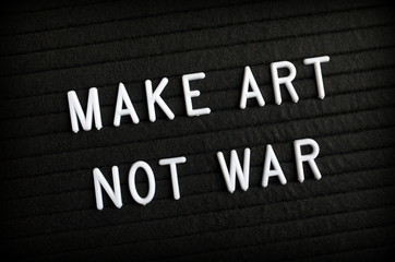 The phrase Make Art Not War in white letters on a notice board as a message of peace
