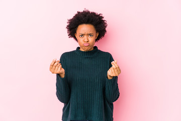Middle aged african american woman against a pink background isolated showing that she has no money.