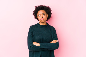 Middle aged african american woman against a pink background isolated tired of a repetitive task.