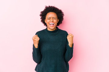 Middle aged african american woman against a pink background isolated cheering carefree and excited. Victory concept.