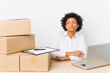 Warehouse manager sitting checking deliveries with laptop dreaming of achieving goals and purposes