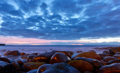 Fototapeta na wymiar Sea after sunset and beach with big stones.