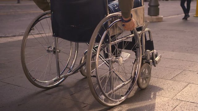 young paraplegic man pushing his wheelchair on crowded pavement