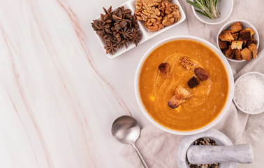 Pumpkin soup with croutons in white bowl decorated with spices top view flat lay with copy space