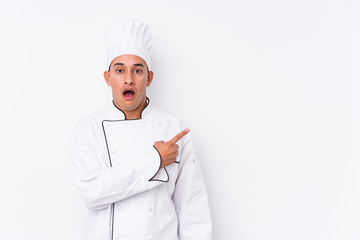 Young latin chef man isolated pointing to the side