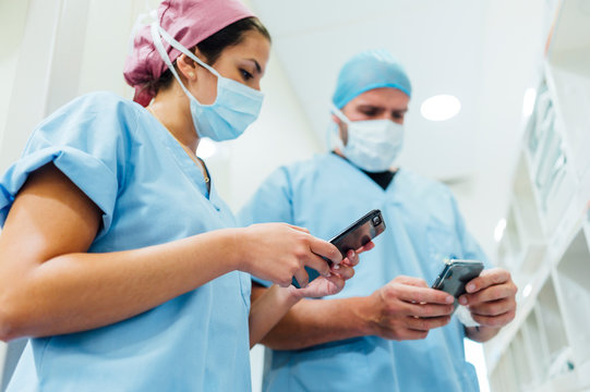 Doctors Using Cell Phones In The Hospital Corridor. Medical Concept