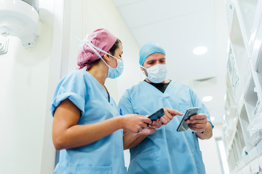 Doctors using cell phones in the hospital corridor. Medical concept