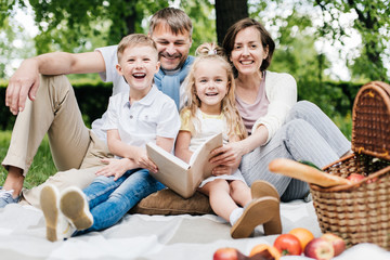 Portrait of a happy family at the picnic with a book.