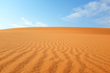 Bright orange desert sand patterns and bright blue sky for a warm summer background