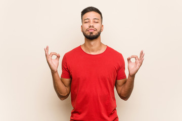 Naklejka premium Young south-asian man relaxes after hard working day, she is performing yoga.