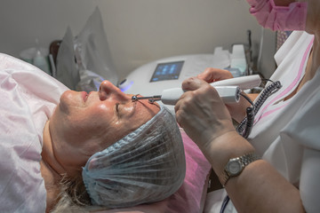 A cosmetic procedure with microcurrent injections in a beauty salon is performed for an aged woman. Improving skin turgor, rejuvenation and healing.