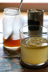 Ginger ale with lemon, with a bottle of homemade ginger syrup and a spoon in the background.
