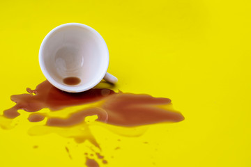 Spilled coffee from a glass onto a yellow background