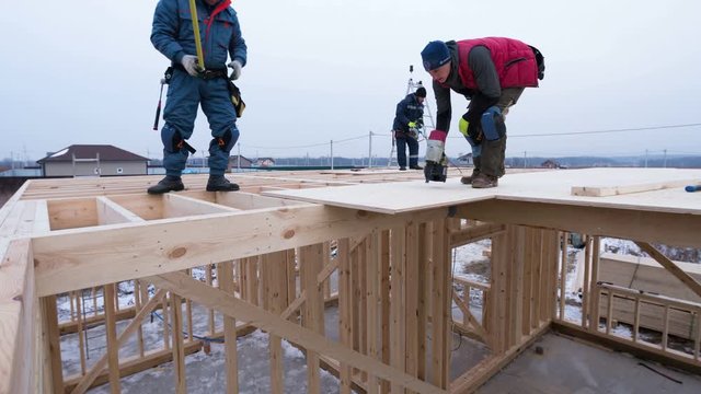 Timelapse zooming out view of builders covering the second floor of house with plywoods. Frame cottage under construction