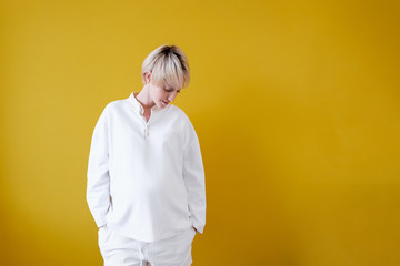 Portrait of a positive stylish beautiful blonde woman in a white suit on a yellow background....