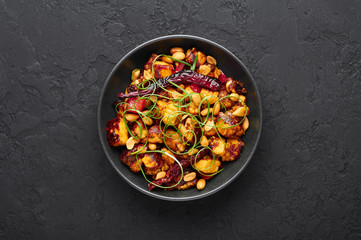 Kung Pao Paneer at black slate background. Kung Pao Paneer is a vegetarian version of chinese sichuan dish Gong Bao with paneer cheese, peanuts, chilli peppers, sauces and onion. Top view. Copy space