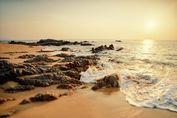 Fototapeta na wymiar Beautiful sunset seascape with rock on sand beach.