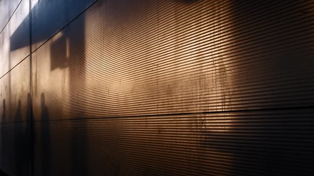 Shadows of walking people at the airport. Background of a metal fence with the shadow of people. Evening time light from the setting sun
