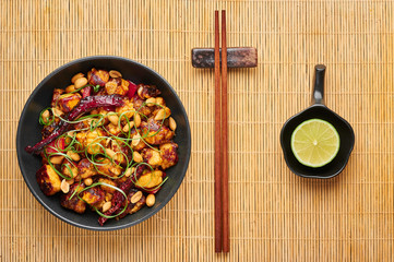 Kung Pao Paneer at black slate background. Kung Pao Paneer is a vegetarian version of chinese sichuan dish Gong Bao with paneer cheese, peanuts, chilli peppers, sauces and onion. Top view