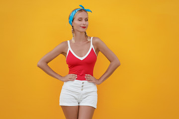 Flirting beauty. Bright portrait of young pretty woman winking and smiling. Yellow background.