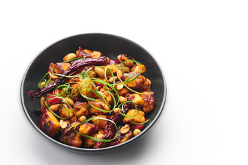 Kung Pao Paneer at isolated on white background. Kung Pao Paneer is a vegetarian version of chinese sichuan dish Gong Bao with paneer cheese, peanuts, chilli peppers, sauces and onion. Copy space