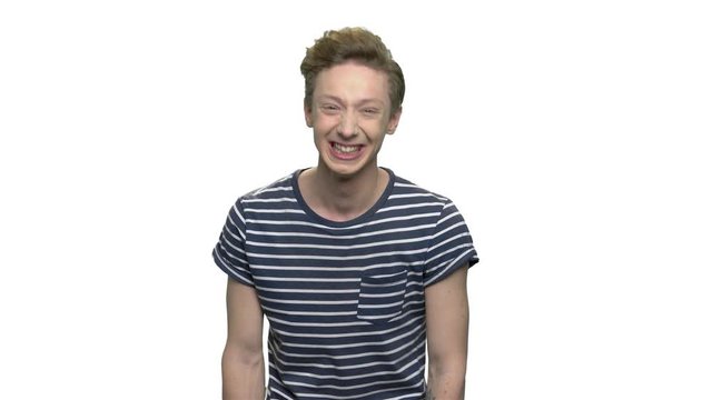 Portrait of expressive teen guy on white background. Emotional teenage boy in striped t-shirt is laughing hard. Emotion and facial expression concept.