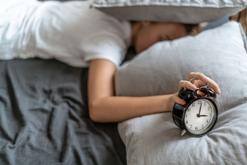 Woman with insomnia lying in bed with her head under her pillow trying to sleep. Insomnia and sleep problems. Relax and sleep concept. Feels sleepy and tired.