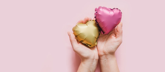 Festive flat lay. Foil heart shaped balloons on a pastel pink background. The concept of love Holiday Valentine's Day or wedding, bachelorette party, birthday.