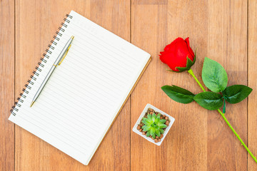 Red roses on wooden table and notepad