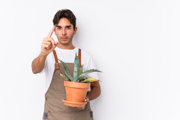 Young caucasian gardener man holding a plant isolated showing number one with finger.