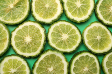 Fototapeta na wymiar Fresh slices of bergamot fruits on green background