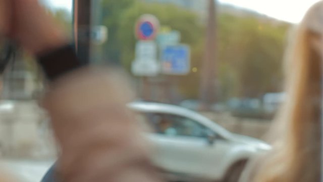 A beautiful blonde woman in sunglasses and take looks at her reflection in the shop window. Cars pass in the background. Paris France.