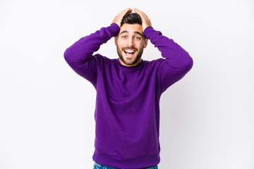 Young caucasian man against a white background isolated laughs joyfully keeping hands on head. Happiness concept.