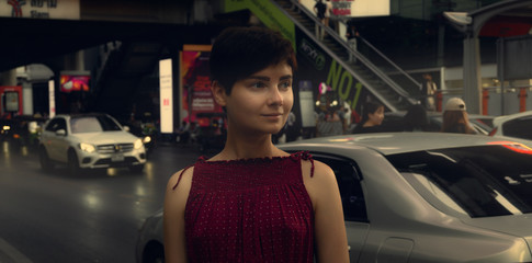 A girl in a red dress walks around Bangkok. Portrait of a girl in a metropolis. Tourism.