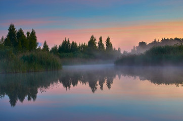 Misty morning on a small lake. Atmospheric sunrise.