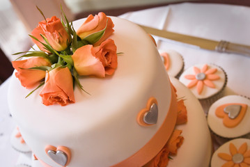 Celebration cake and cup cakes iced in pale orange roses and shapes