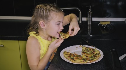 Smart girl learning to cook. Happy and serious young mistress children to cook a Neapolitan egg fried omelette from sausage. Modern Built In Kitchen Appliances in green black color.