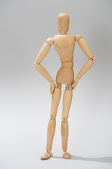 Wooden dummy with hands on hips on grey background