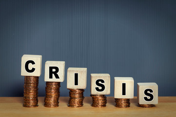 Stacking coins and wooden block with word crisis. Economy and Financial crisis concept