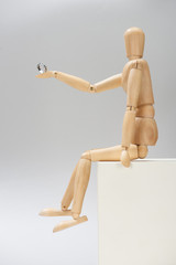 Wooden puppet with silver ring on white shand on grey background